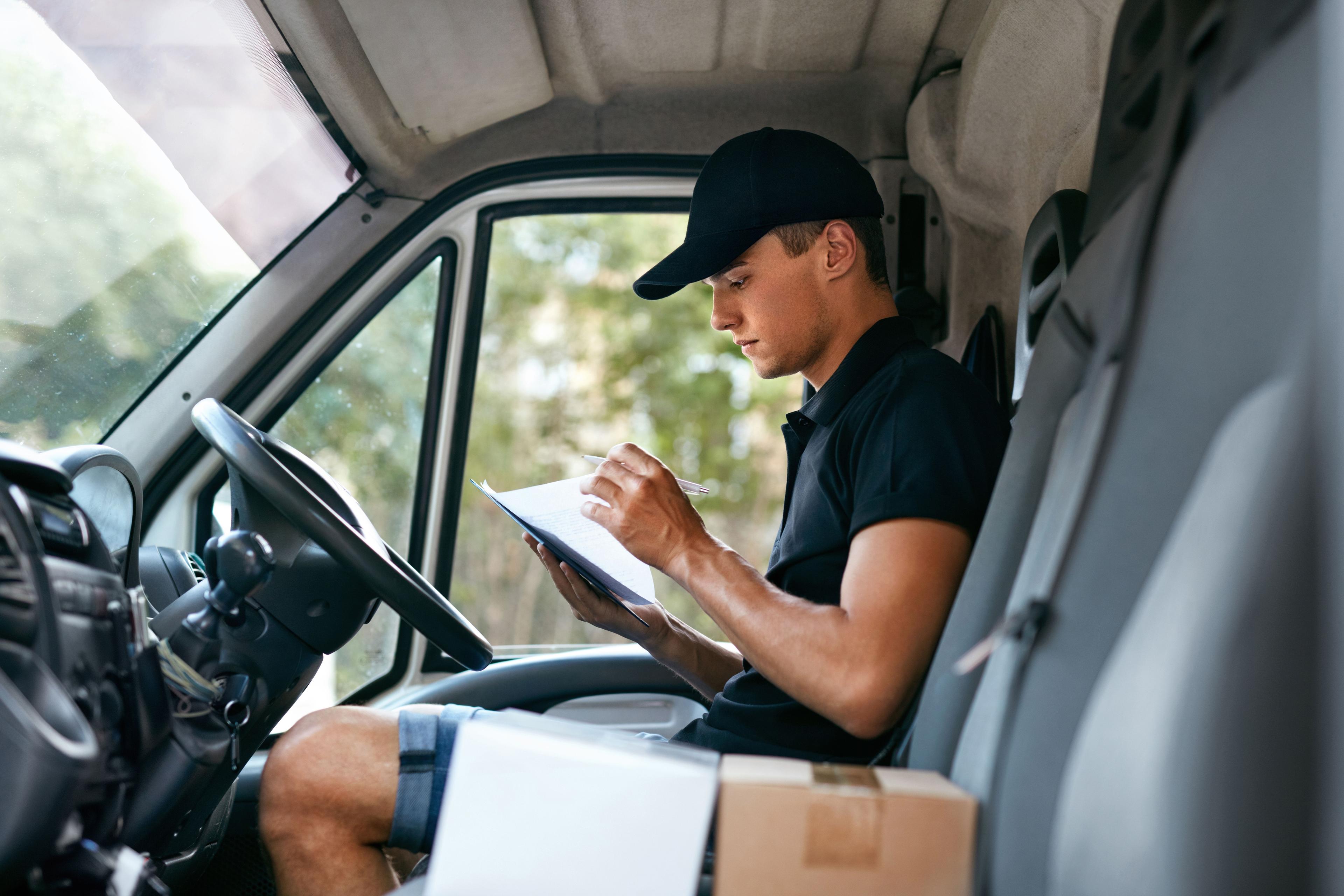 Courier driver in the front seat of their van looking over paperwork