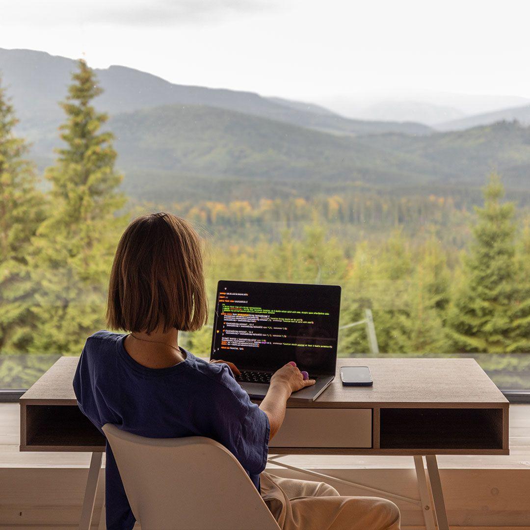 Someone working at a desk looking out over a forest